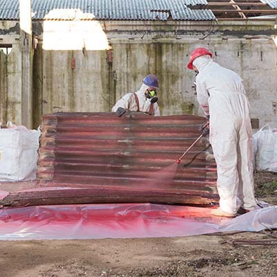 Man spraying down tarp after environmental remediation services