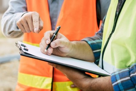 An environmental professional calculating phase 1 ESA cost on a clipboard