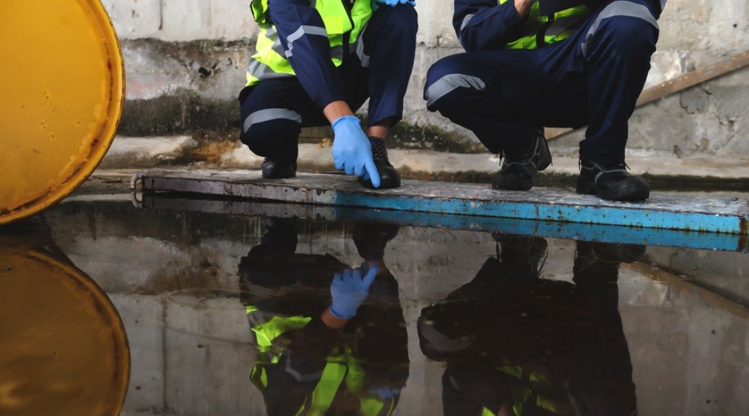 Workers standing over a fuel spill pointing at it