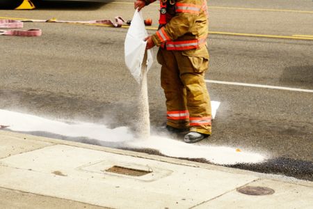 Worker dumping absorbent material on spill