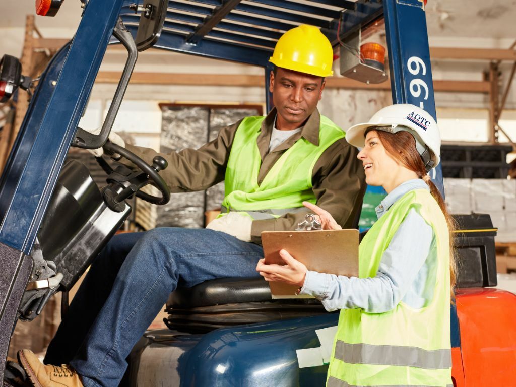 Driver sitting in a forklift and being given instructions by a trainer