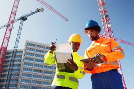 OSHA inspector with checklist on construction site with worker