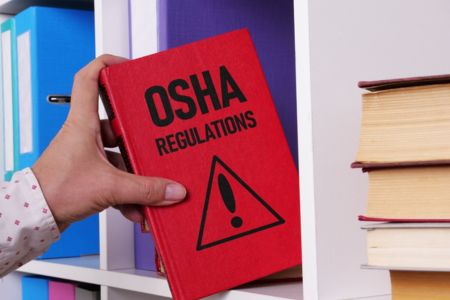 Person reaching for OSHA regulations handbook