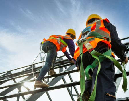 a group of men wearing safety vests and helmets climbing scaffolding