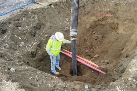 worker performing vacuum excavation in trench