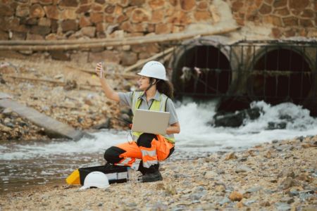 Female Engineer Testing Water Near A Drainage.