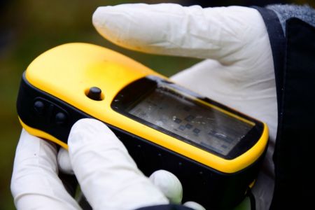 Gloved Hands Holding A Yellow Radiation Detector