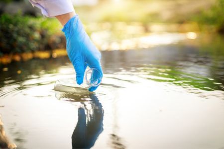 Scientist takes samples of factory wastewater in a test tube.
