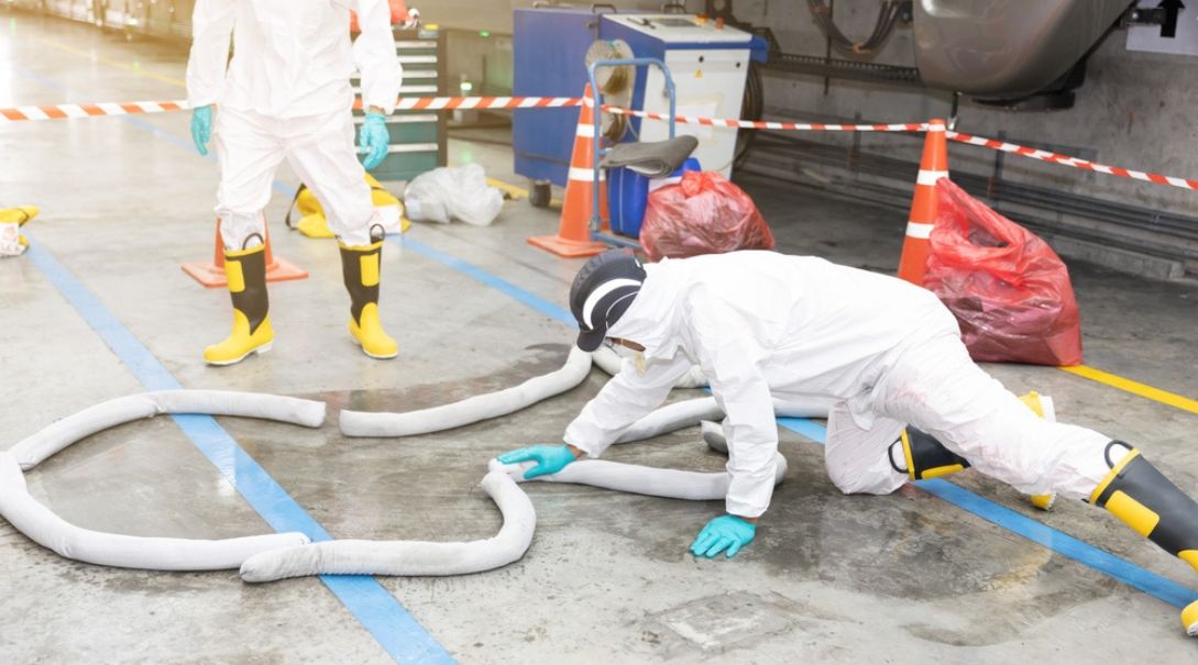 industrial team deploying absorbent booms for waste oil spill containment