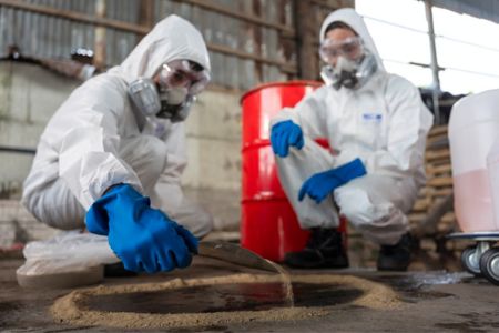 hazmat technicians collecting and inspecting contaminated waste oil