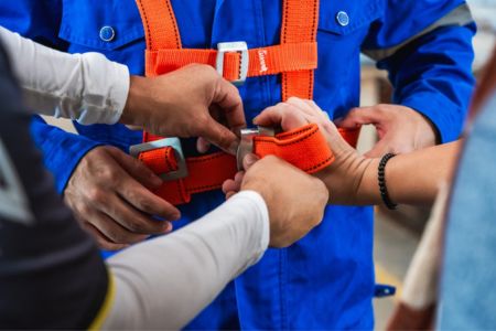 workers adjusting safety harness during training